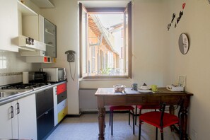 A kitchen with a window, a table with chairs, and a stove. - VICOLO LAVANDAI - Petit Apartment Navigli (Milano)