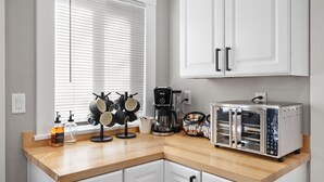 A kitchen with white cabinets, a toaster oven, a coffee maker, and a rack with pots and pans. - Emma s Manor A Down Town Prescott Gem (Prescott)