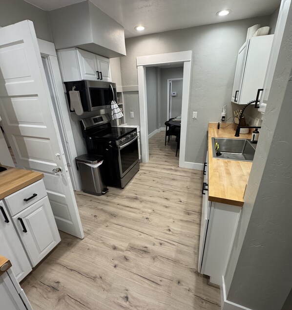 A compact kitchen with white cabinets, a black stove, and a wooden countertop.
