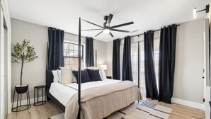 A modern bedroom with a large bed, a ceiling fan, and black curtains. - Emma s Manor A Down Town Prescott Gem (Prescott)