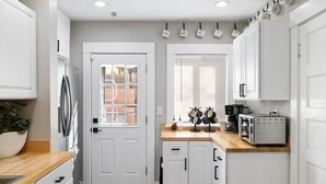 A modern kitchen with white cabinets, a stainless steel refrigerator, a toaster, and a coffee maker. - Emma s Manor A Down Town Prescott Gem (Prescott)