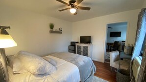 Ein Schlafzimmer mit Bett, Deckenventilator, Fernseher und Stuhl.