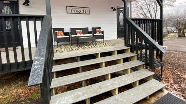 Eine Veranda mit einem Schild, auf dem 'PORCH' steht, und einer Treppe, die dazu hinauf führt.