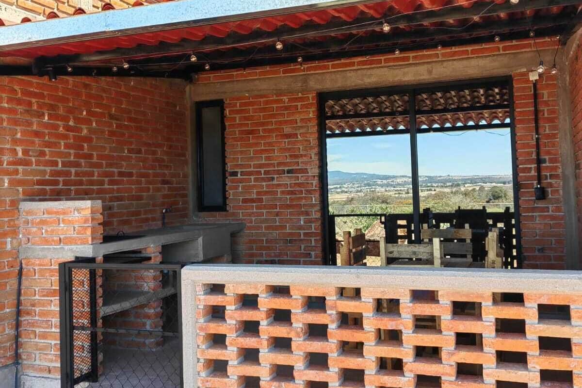 Una casa in mattoni con un patio, una ciminiera e vista sul paesaggio.