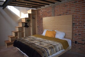 A bedroom with a brick wall, a wooden headboard, a bed with a patterned blanket, and built-in wooden shelves. - Cabañas El Campo (Amealco)