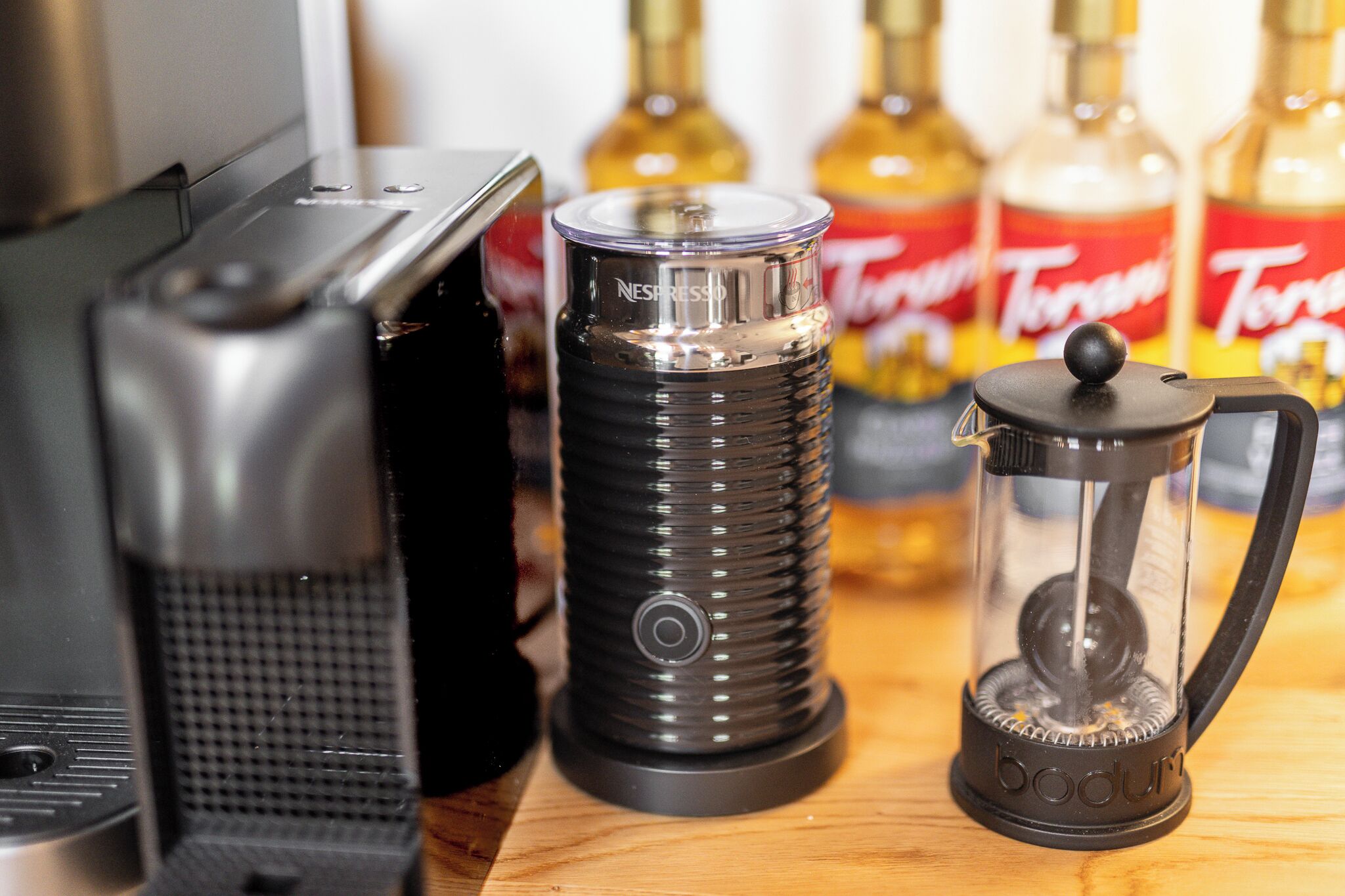 A coffee maker, a Nespresso machine, and a Toddy on a wooden surface.
