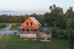 A wooden cabin with a porch, a covered outdoor seating area, and a fire pit.