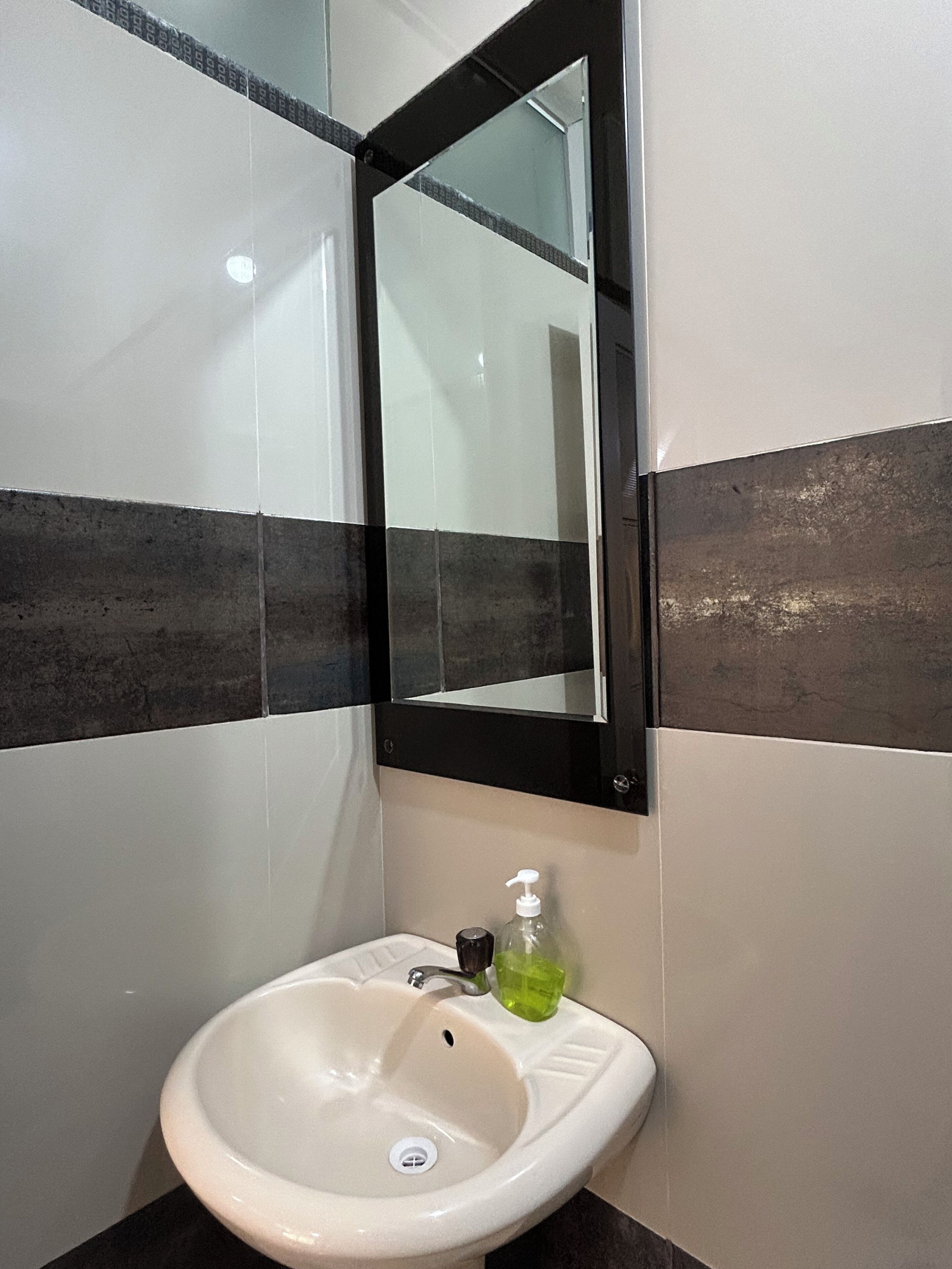 A bathroom with a white sink, a mirror, and a soap dispenser.
