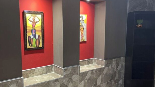 A hallway with red walls, two framed artworks, and a stone-tiled floor. - CASA LUNA - Complete lodging (Salta)