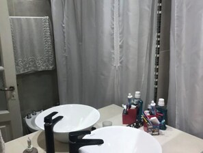 Un baño con dos lavamanos, un perchero y artículos de aseo en la encimera.
