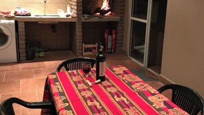 An outdoor kitchen with a brick oven, a washing machine, and a table set for dining. - CASA LUNA - Complete lodging (Salta)