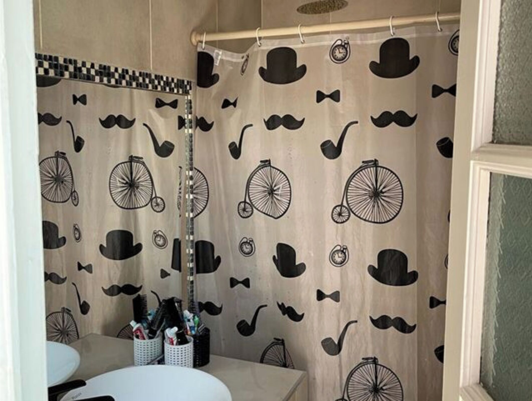 A bathroom with a patterned shower curtain, a sink, and a mirror.