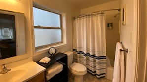 Une salle de bain avec un lavabo, des toilettes et un rideau de douche.