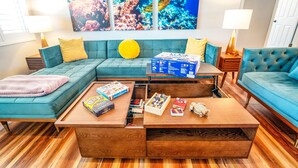 Ein Wohnzimmer mit einem petrolfarbenen Sofa, einem Holztisch und einer großen Aquariumwand.