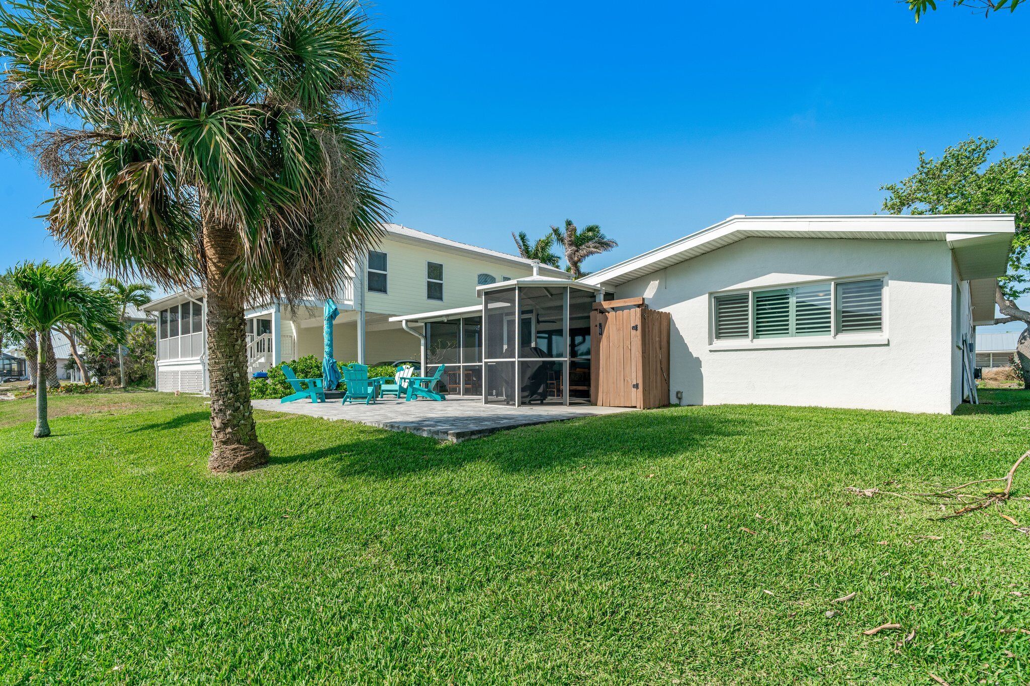A modern house with a covered patio, a lawn, and a palm tree.