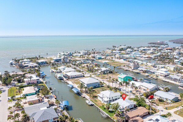 Vista aérea de una zona residencial costera con casas, un puerto deportivo y una vista despejada del océano.