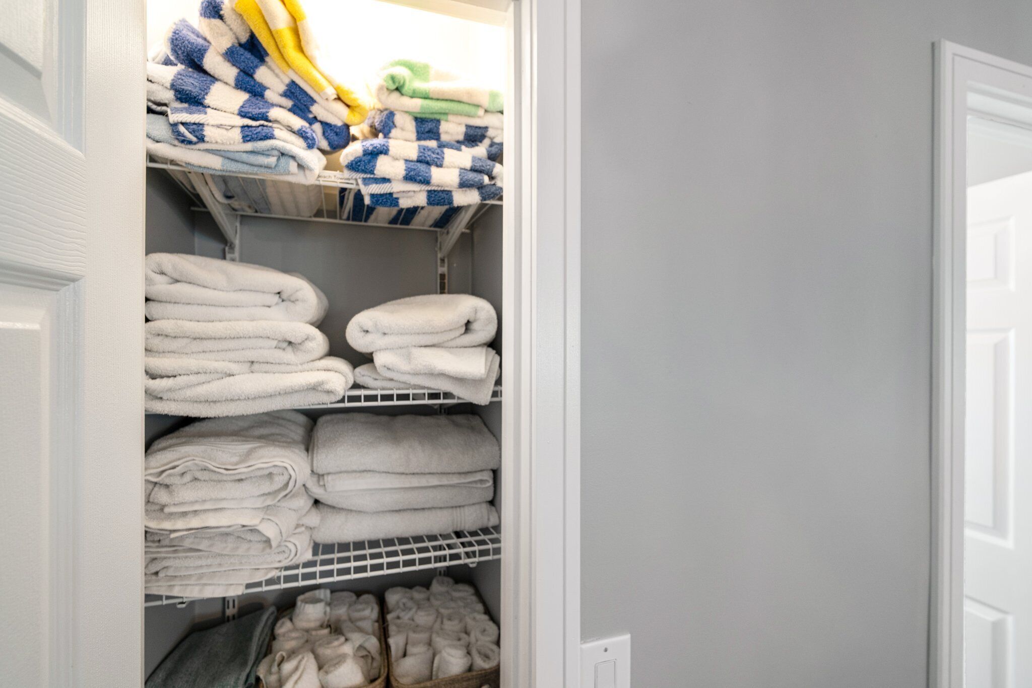A storage closet with shelves holding folded towels and bathrobes.