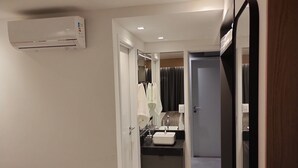 A hotel room with a bed, a bathroom with a sink and mirror, and a wardrobe. - Apto 00203 Legacy Suites  (João Pessoa)