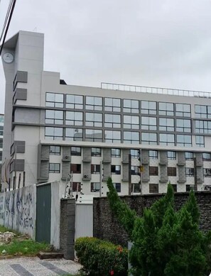 Un edificio moderno con techo plano, ventanas grandes y una pared de piedra en la base.