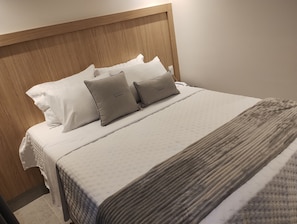 A neatly made bed with a wooden headboard, two pillows, and a textured blanket.