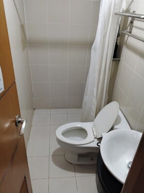 Une salle de bain avec des toilettes blanches, un lavabo et un rideau de douche.