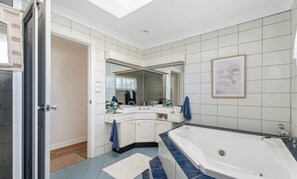 A modern bathroom with a large bathtub, a walk-in shower, and a double vanity.