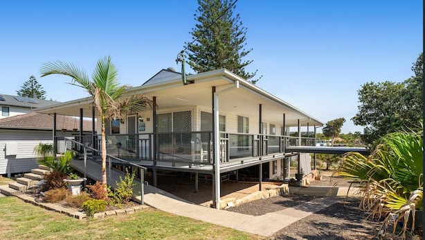 A modern house with a covered porch, a staircase leading to the entrance, and a garden with various plants. - Anna Bay Beachside Getaway (Anna Bay)
