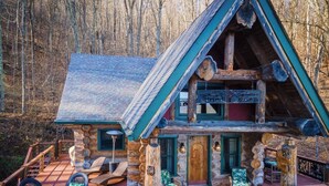 Une cabane en rondins dotée d’une terrasse, d’une enseigne indiquant « Jardina Springs » et d’une façade rustique.