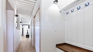 A hallway with white walls, a wooden floor, and a bench with a wooden top.