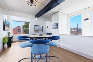 A modern dining area with a round table and blue upholstered chairs, large windows with city views, and a ceiling fan. - Awesome Custom Built Home. Perfect Indy Location! (Indianapolis)