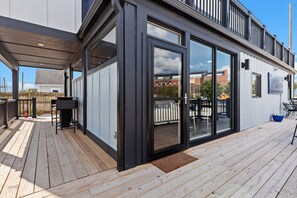 A modern building with a wooden deck, large sliding glass doors, and a visible outdoor seating area. - Awesome Custom Built Home. Perfect Indy Location! (Indianapolis)
