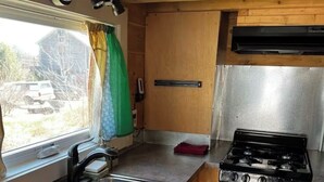 A compact kitchen with a sink, stove, and wooden cabinets.