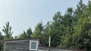A small cabin with a wooden exterior, multiple windows, and a chimney.