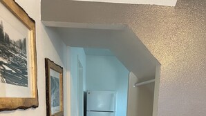 A hallway with a patterned rug, a refrigerator, and framed pictures on the wall. - Charming Room 6 in the St. Maries Inn (Saint Maries)