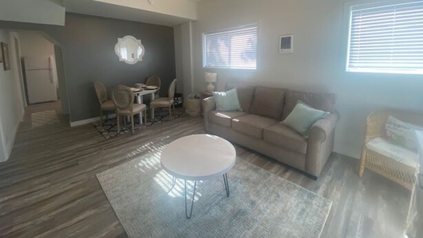 A living room with a ceiling fan, a sofa, a coffee table, and a dining area with chairs. - Charming Room 6 in the St. Maries Inn (Saint Maries)