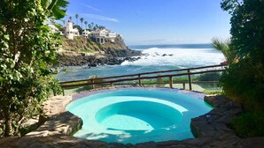 A pool with a view of the ocean and a cliffside building. - PrivateJacuzzi-LasOlasCondo-Pool&Jacuzzis-Rosarito (Playas de Rosarito)