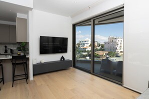 Une cuisine moderne dotée d’un grand téléviseur, d’un plancher en bois et offrant une vue sur la ville grâce à de grandes fenêtres.