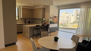 Eine moderne Küche mit einer großen Kochinsel, Barhocker und einem Essbereich mit rundem Tisch und Stühlen.