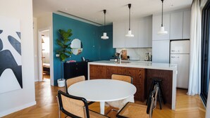 A modern kitchen with a central island, white cabinets, and pendant lighting.