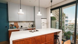 A modern kitchen with white cabinets, a wooden island, and hanging pendant lights.