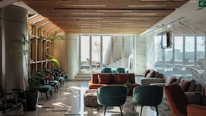 Un lobby moderno con techo de madera, zona de estar y ventanas amplias.