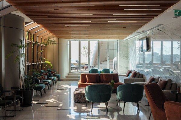 Un lobby moderno con techo de madera, zona de estar y ventanas amplias.