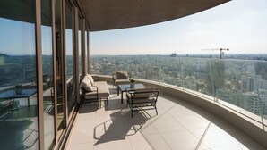 Un balcón moderno con vista a la ciudad, amueblado con un sofá, sillas y una mesita.