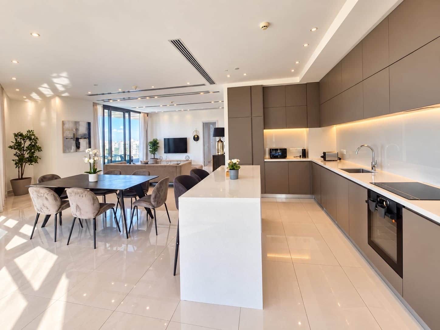 A modern kitchen with a central island, built-in appliances, and a dining area with a large table and chairs.
