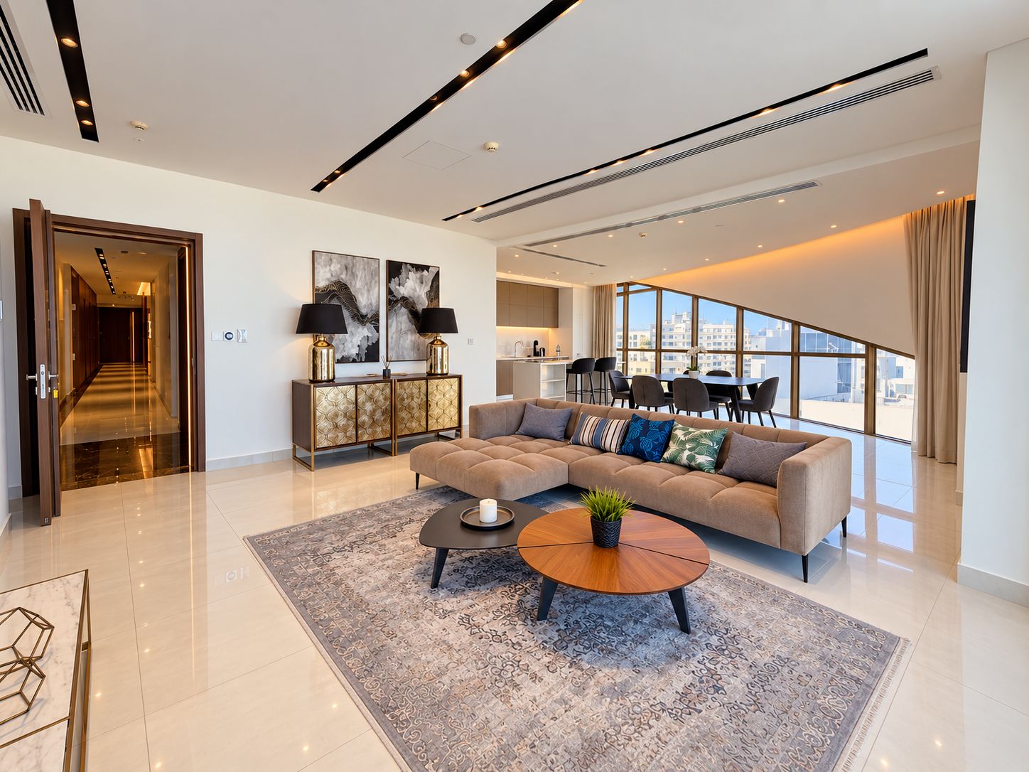 A modern living room with a sectional sofa, a coffee table, and a dining area with a view.