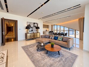 Een moderne woonkamer met een modulaire bank, een salontafel en een eethoek met uitzicht.