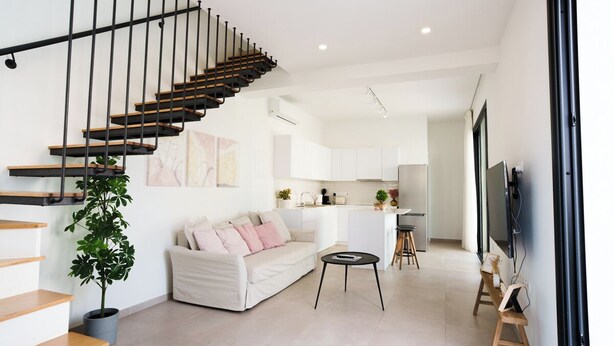 A modern living space with a staircase, a sofa, a coffee table, and a kitchen area. - WealthyStays 2BR Retreat | 5Min Walk to Beach (Protaras)
