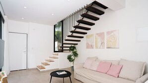 A modern living room with a staircase, a sofa, a coffee table, and artwork on the wall. - WealthyStays 2BR Retreat | 5Min Walk to Beach (Protaras)
