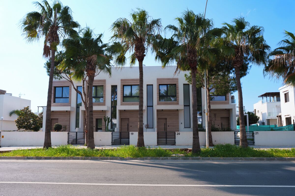 Un immeuble résidentiel moderne à plusieurs étages, doté d’un toit plat, de grandes fenêtres et d’une série de portes numérotées de 19 à 21.