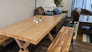 Una mesa de madera para comer con bancos, un sofá y una mesita con plantas.